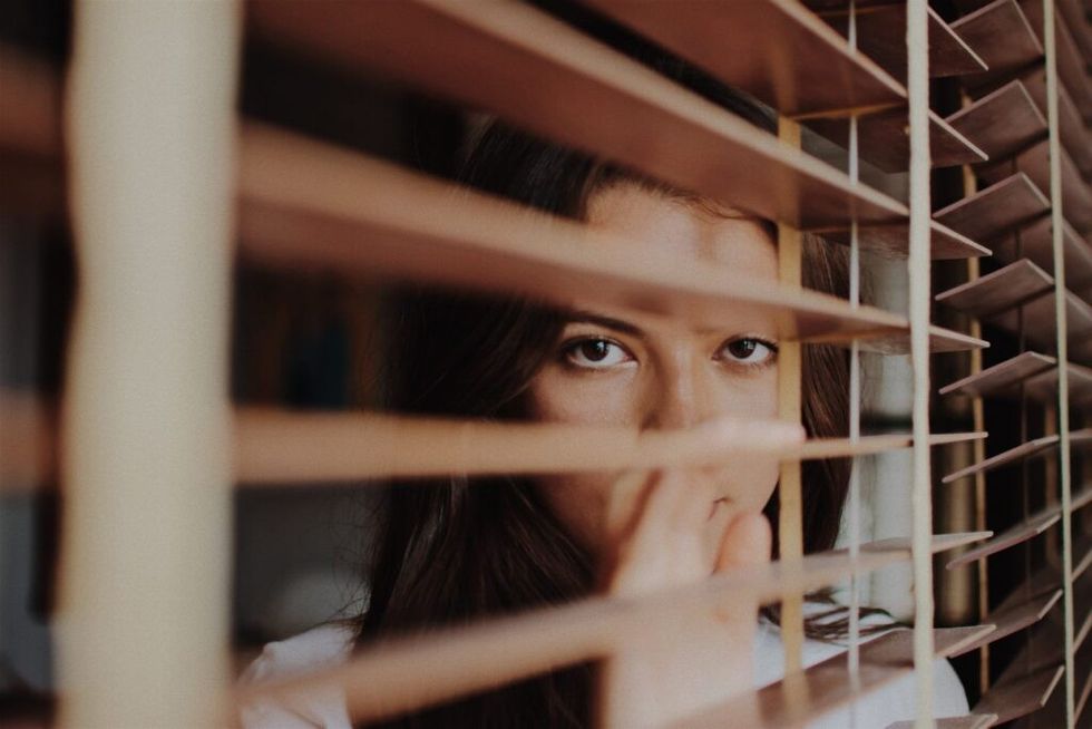 shy-woman-looking-through-blinds