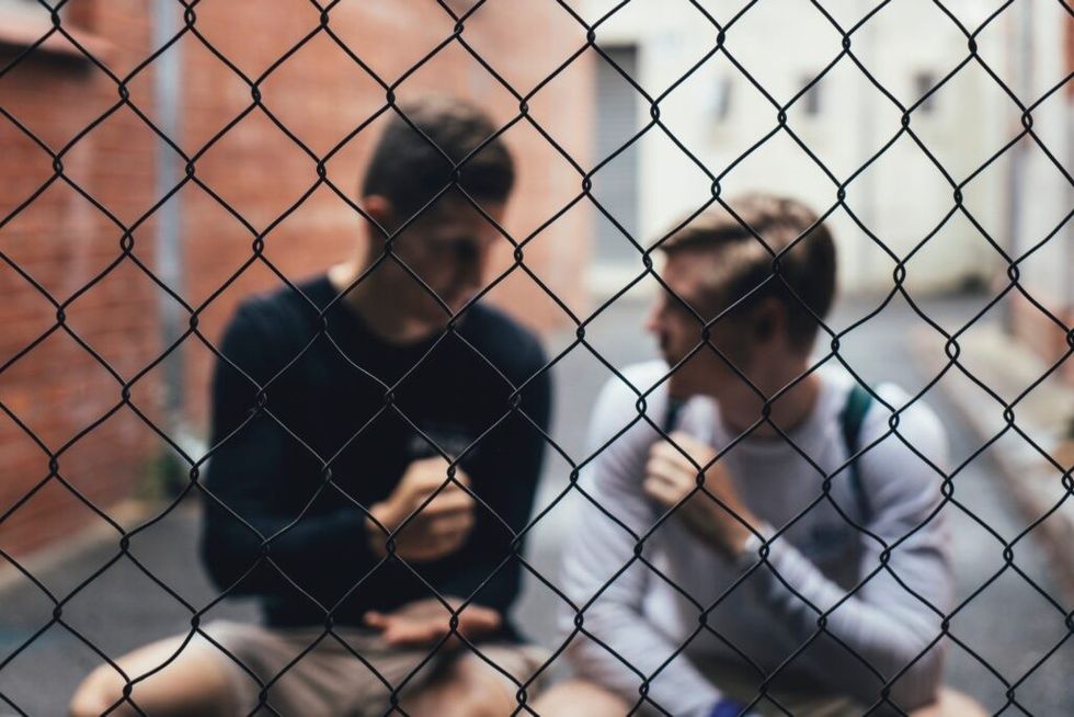 Two-guys-talking-behind-a-fence