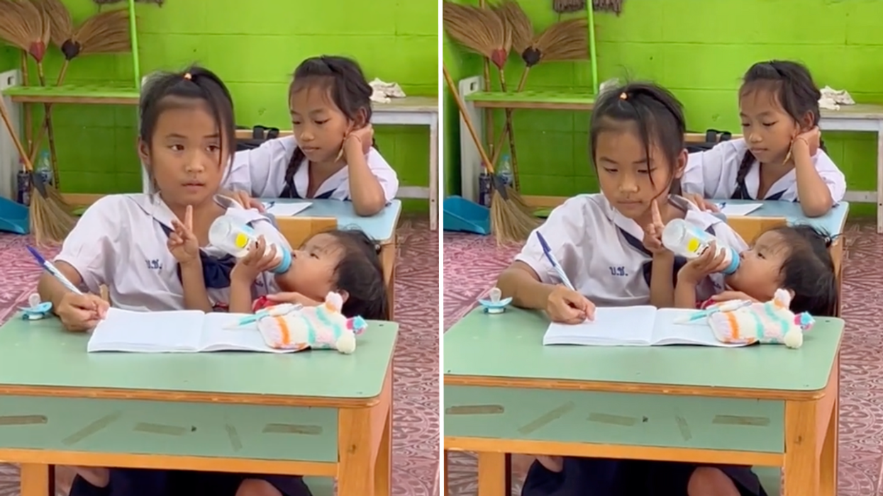 10-year-old student feeds baby sister and simultaneously takes notes in classroom.