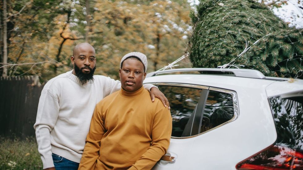 2 men standing in front of a white car
