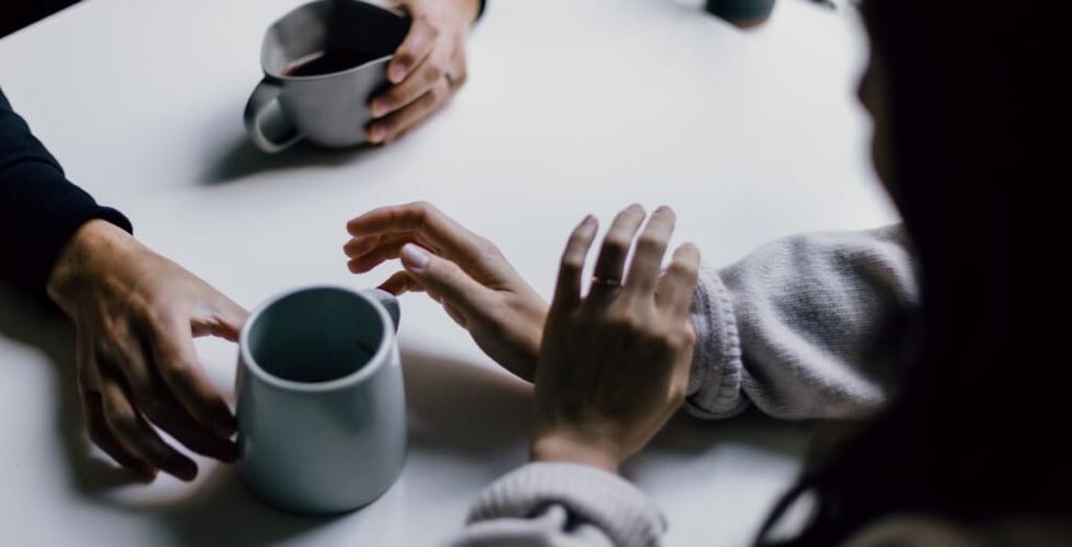 a couple chats over coffee at a table