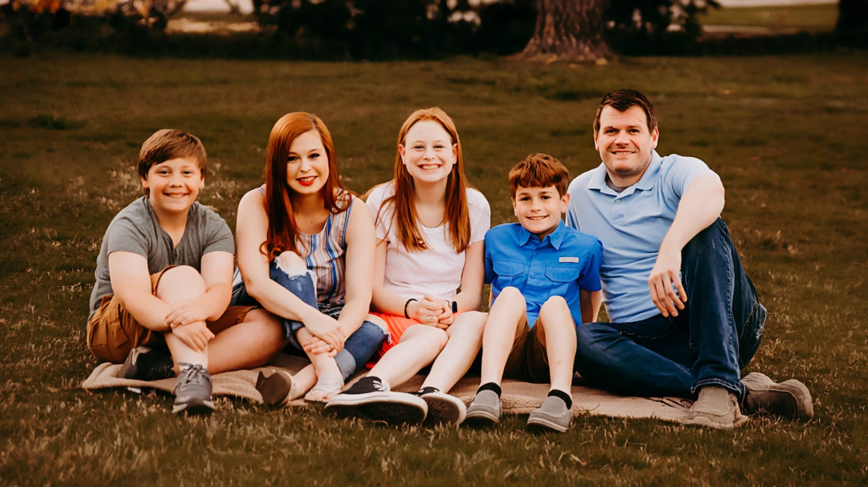 A family sitting on the ground and posing for a picture.
