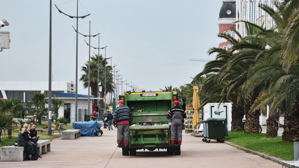 a garbage truck with two sanitation workers