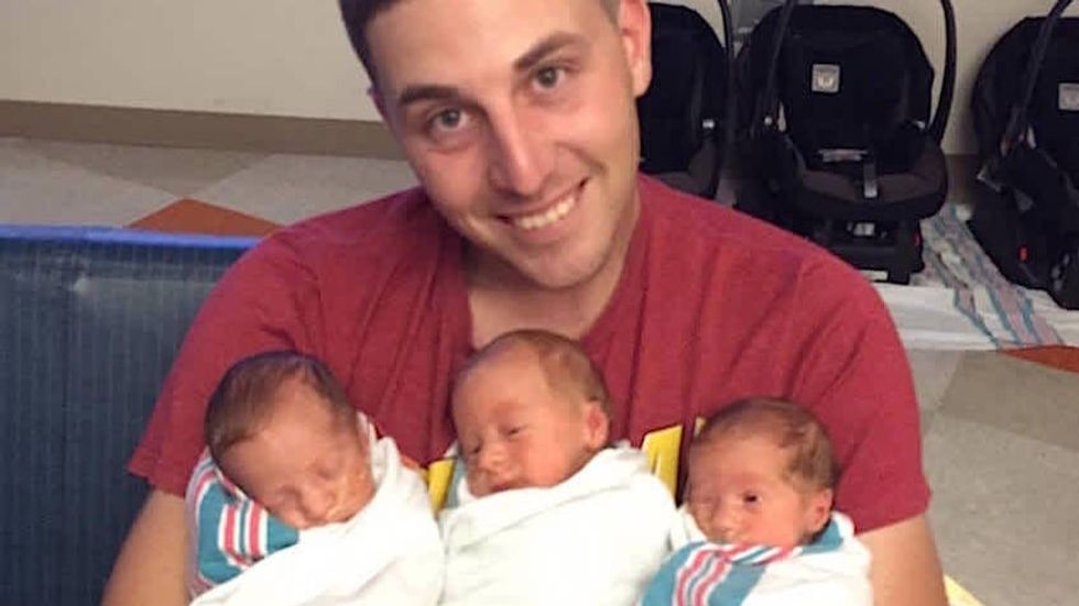 a man holding 3 babies in his arms