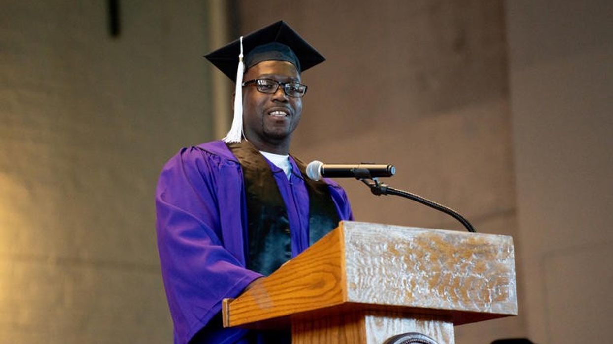 A man standing at a podium wearing a graduation cap and gown.