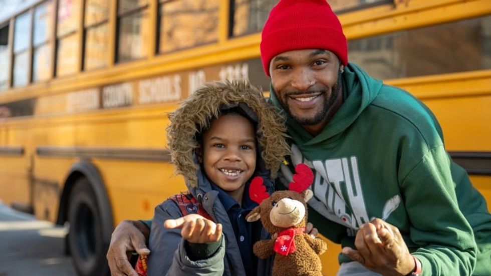 a man with a little boy in front of a school bus