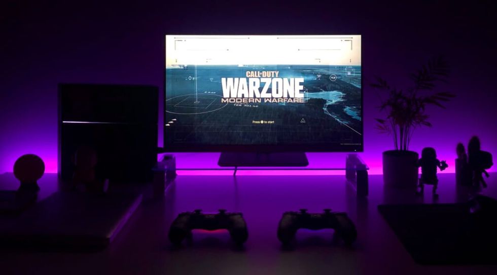 a TV in a dark room with purple lights with "warzone" on the screen