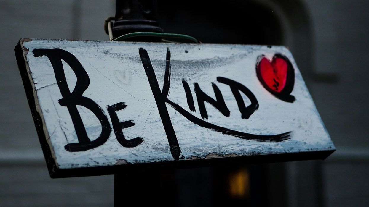A white sign with "be kind" and a red heart written on it.