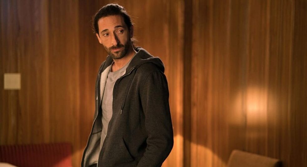 Adrien Brody with long hair in ponytail, wearing a hoodie.