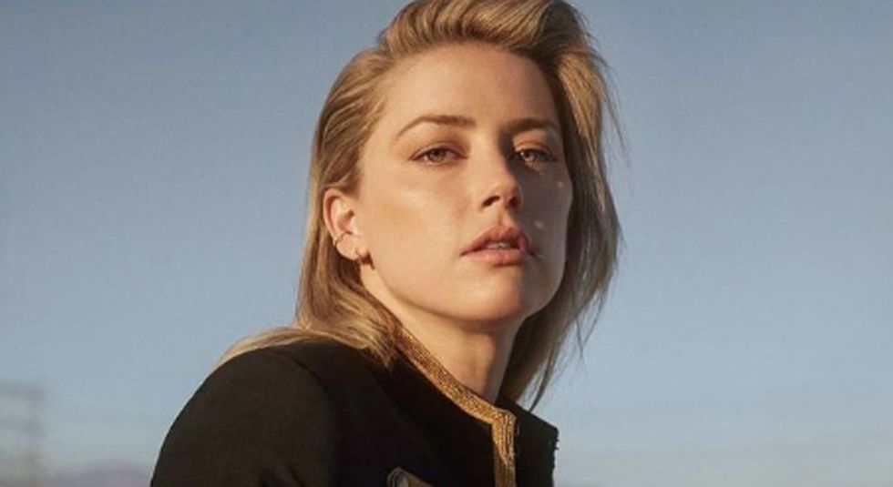 Amber Heard in black jacket staring at the camera.