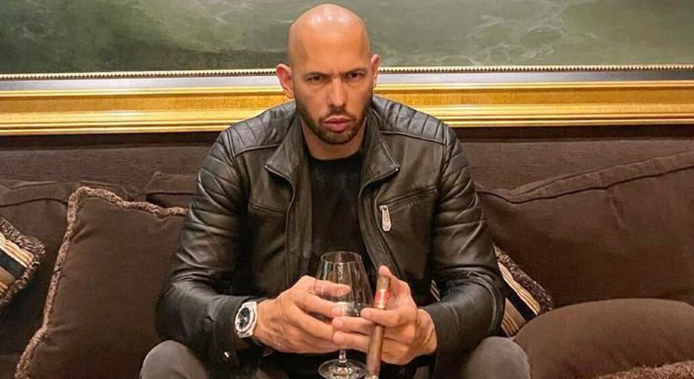 Andrew Tate smoking a cigar and drinking wine.