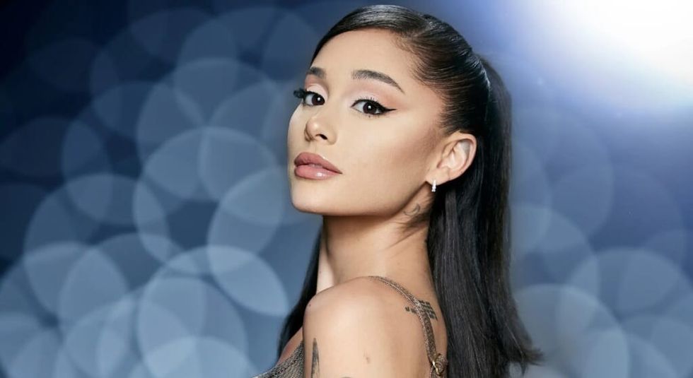 Arian Grande with hair in ponytail showing off her butterfly tattoos.