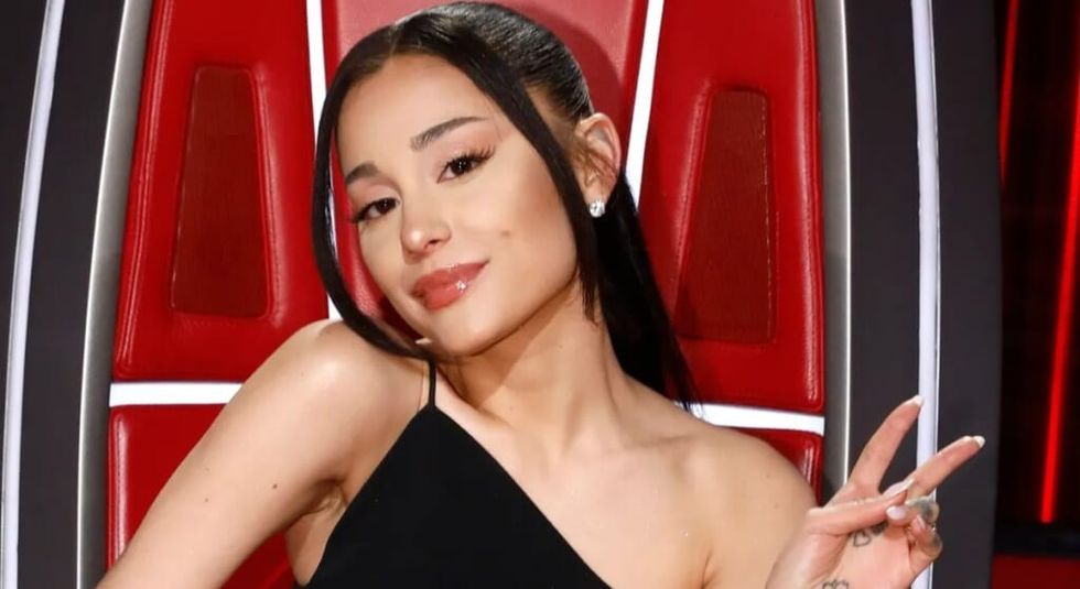 Ariana Grande in a black dress giving the peace sign.