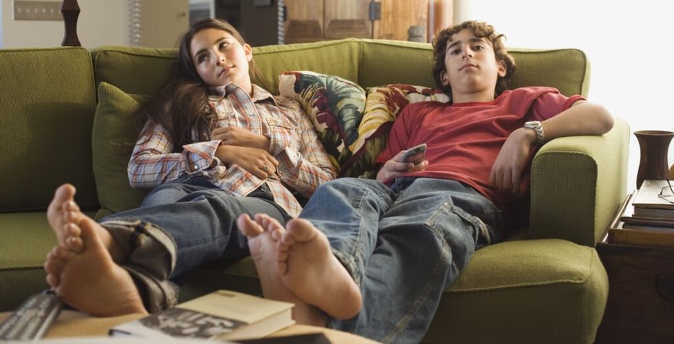 Boy and girl sitting on sofa with remote control