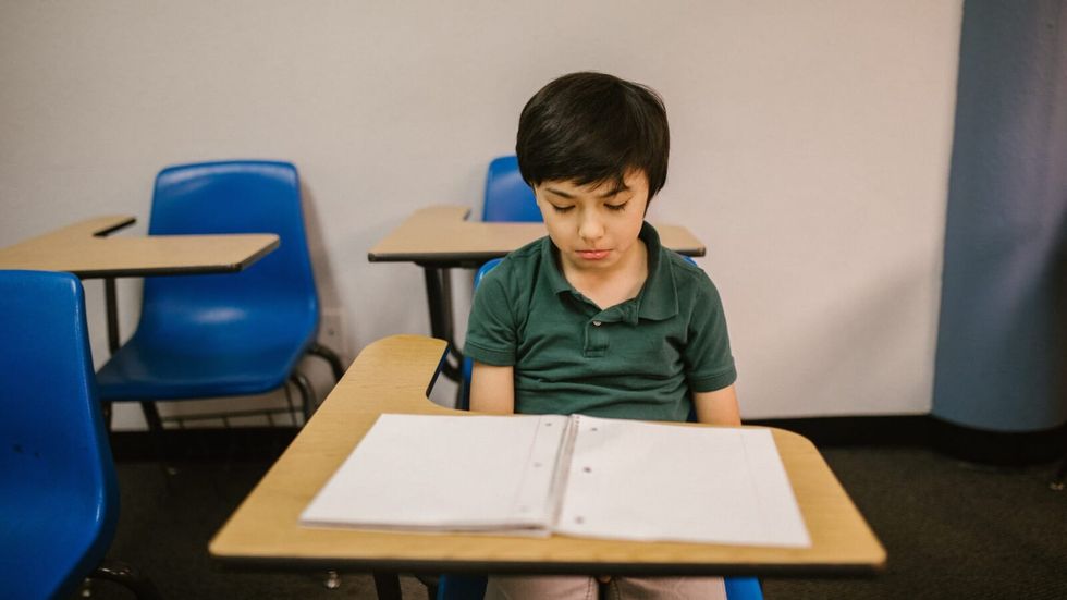 boy sitting at school desk looking sad