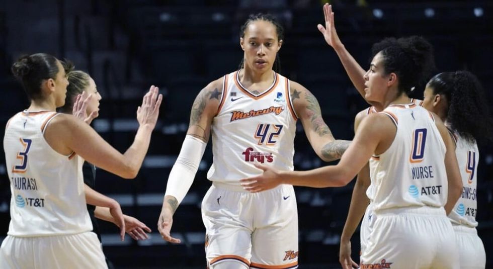 Brittney Griner and team high-fiving in white US basketball uniforms.