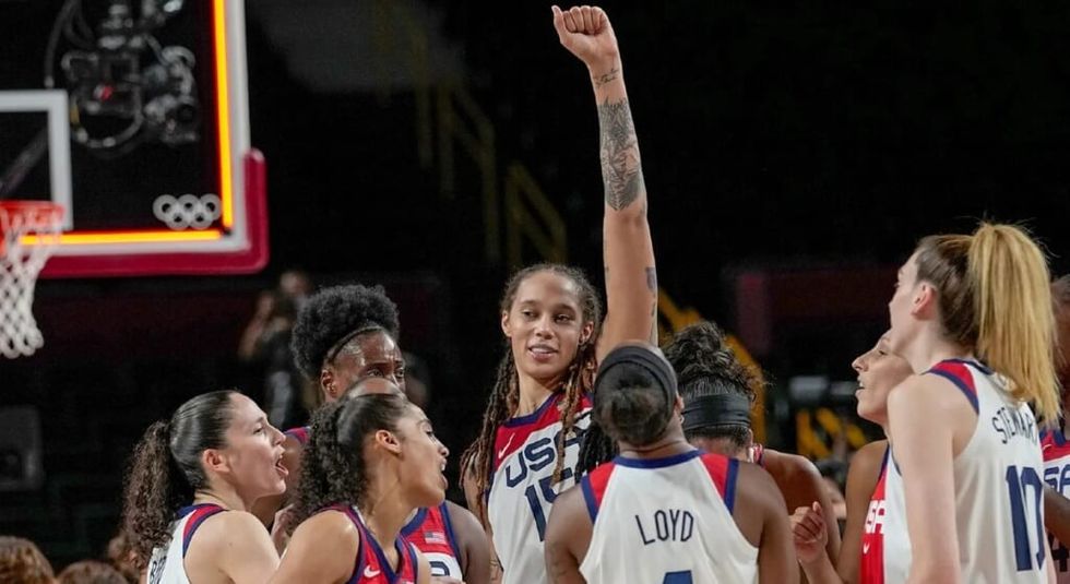 Brittney Griner with her team all wearing their uniforms and cheering.