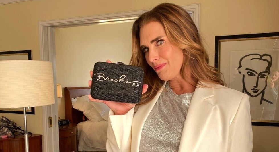Brooke Shields in white suit holding a Brooke sign.