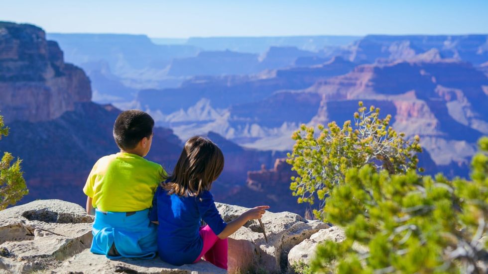 brother and sister sitting at the edge of a cliff