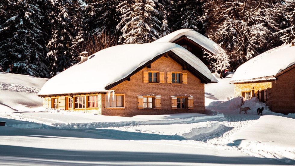 cabin surrounded and covered by snow