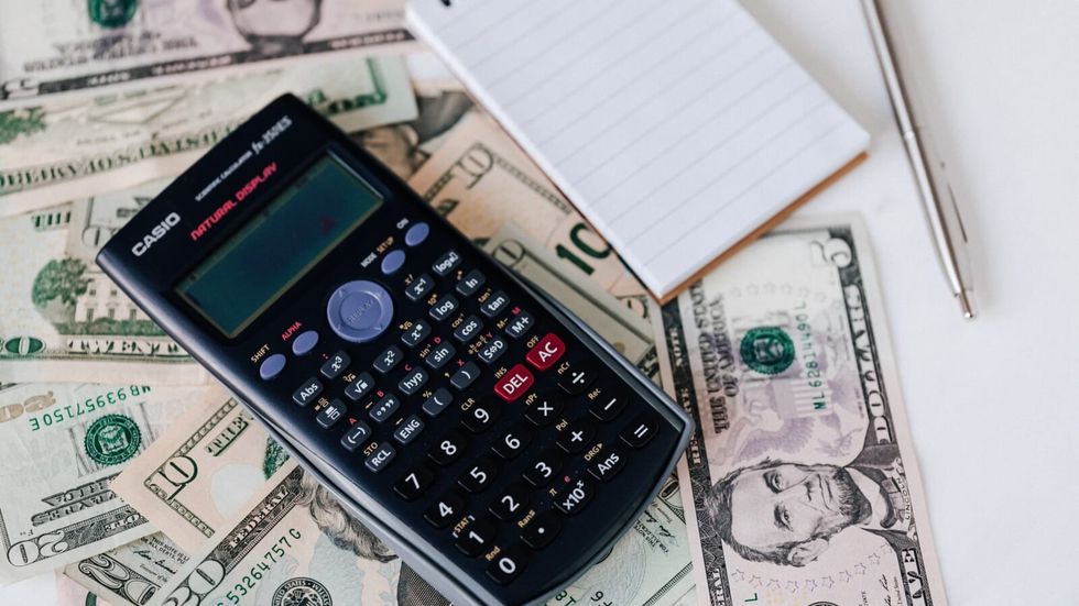 calculator and notepad lying on money
