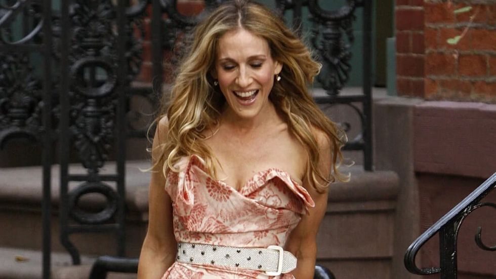 Carrie from Sex in the City walking down the street in a pink dress