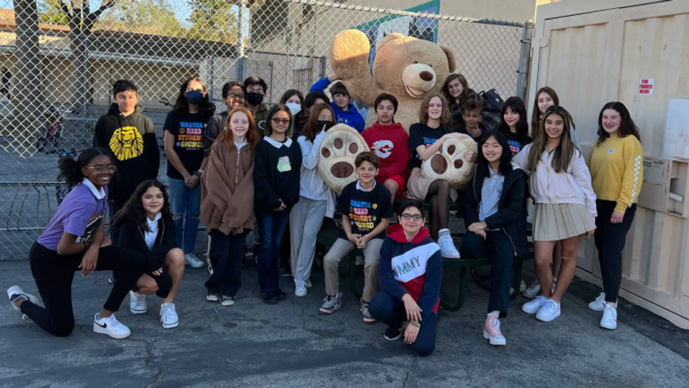 children standing with a huge teddy bear soft toy