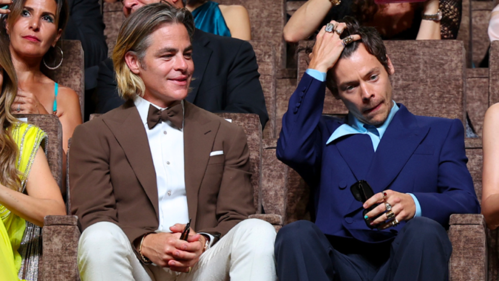 Chris Pine is seated next to Harry Styles at the Don't Worry Darling premiere in Venice. He is smiling in Harry's direction.