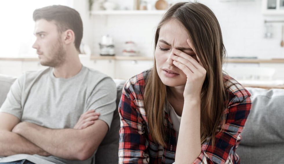 Couple conflict. Stressed crying female sitting on couch with abusive husband after quarrel, ready to divorce
