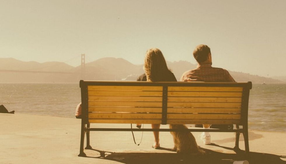 couple sit on bench on sunny day
