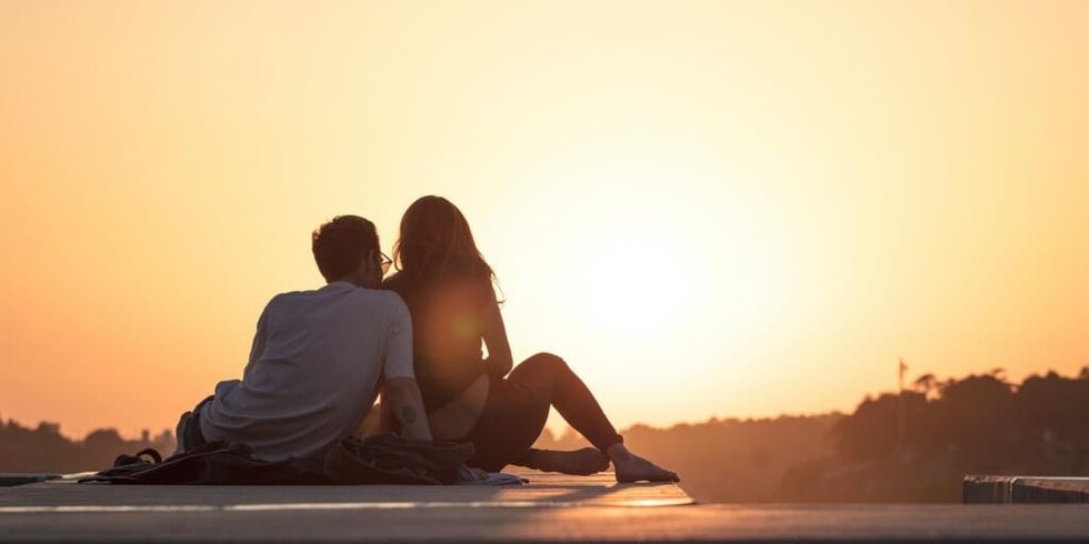 Couple sitting on a rooftop at sunset by Khamkeo Vilaysing on Unsplash