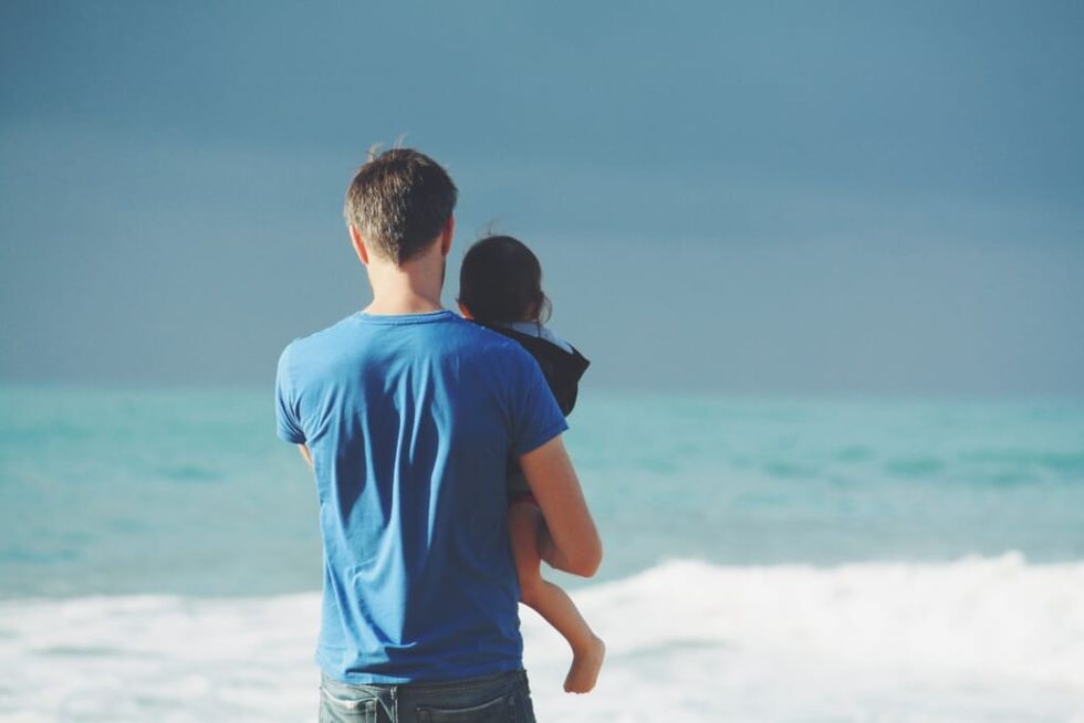 dad and baby on beach looking out on water