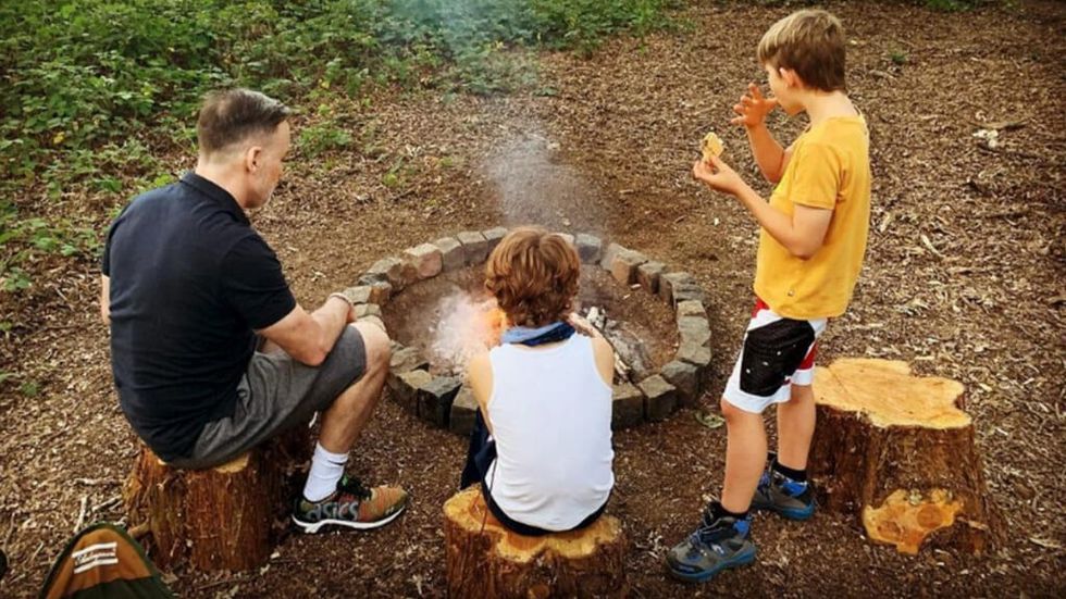 David Furnish with his children around a campfire