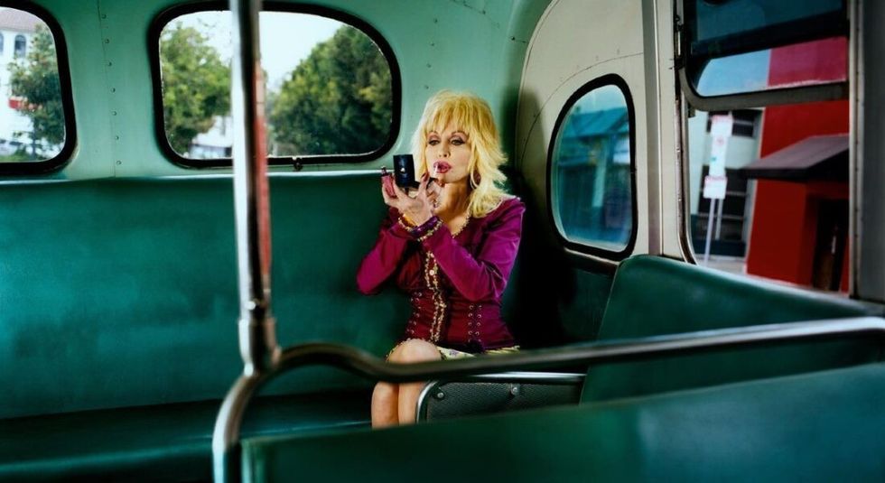 Dolly Parton applying lipstick on a bus.