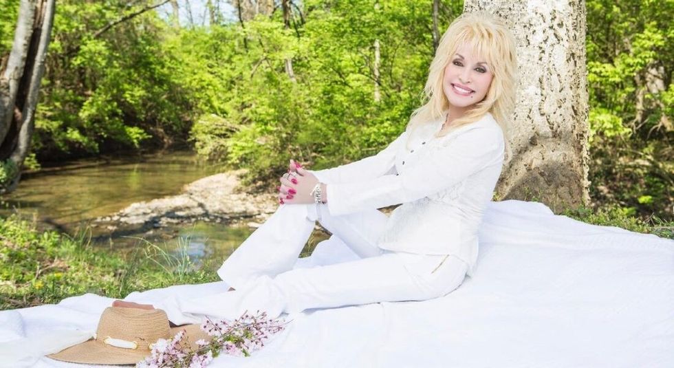 Dolly Parton in all white sitting outside.