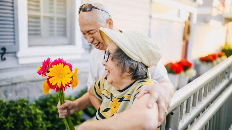 elderly couple holding flowers