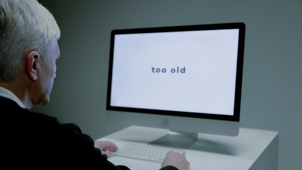 elderly man sitting in front of a computer with