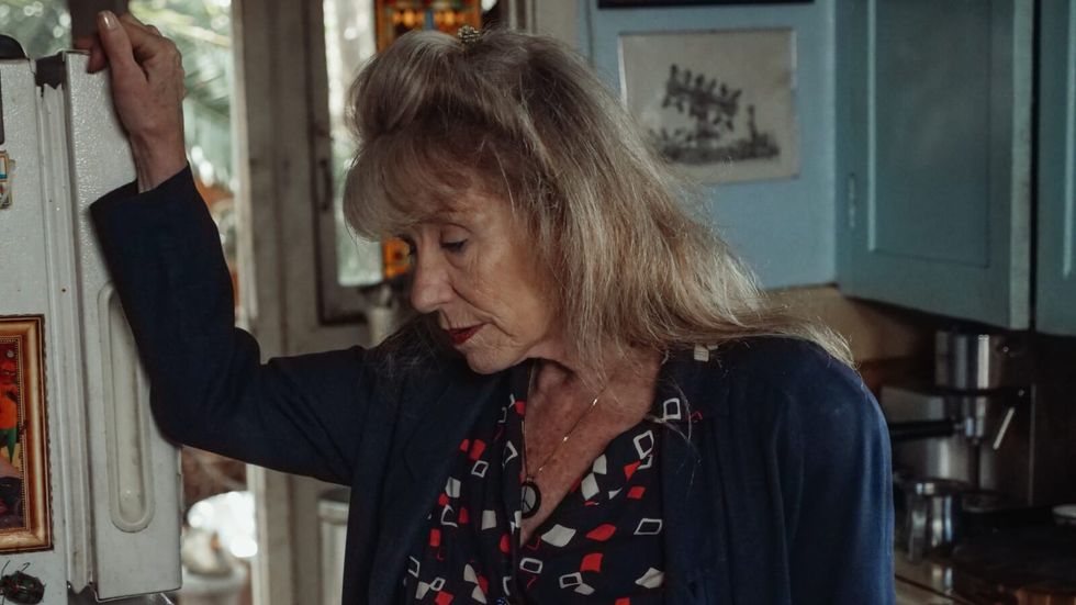 elderly woman leaning against a wall