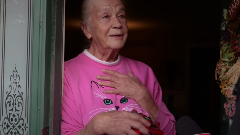 elderly woman wearing a pink sweater with a cat image on it