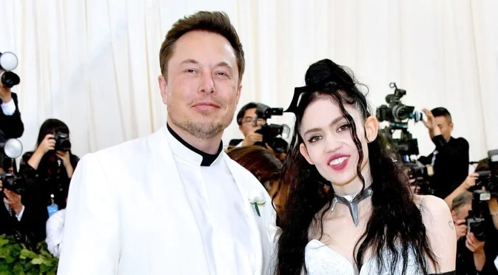 Elon Musk in a white tux posing with his girlfriend Grimes.