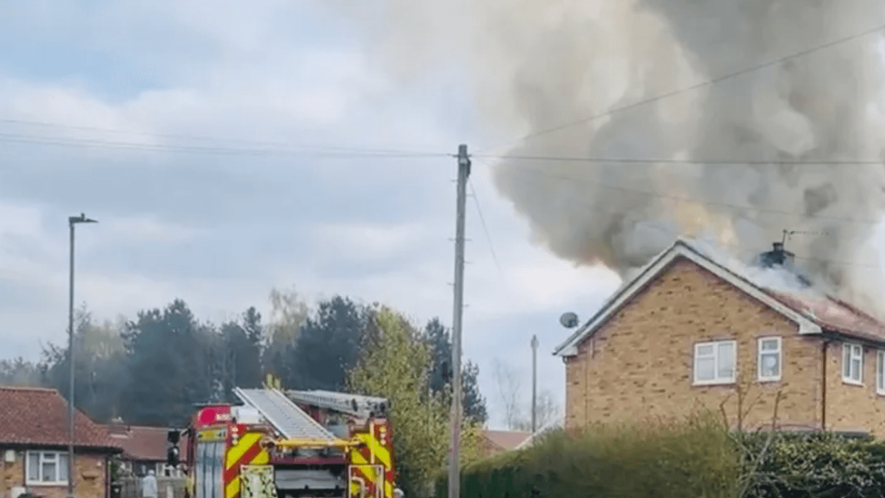 Fire truck parked in front of a house on fire.