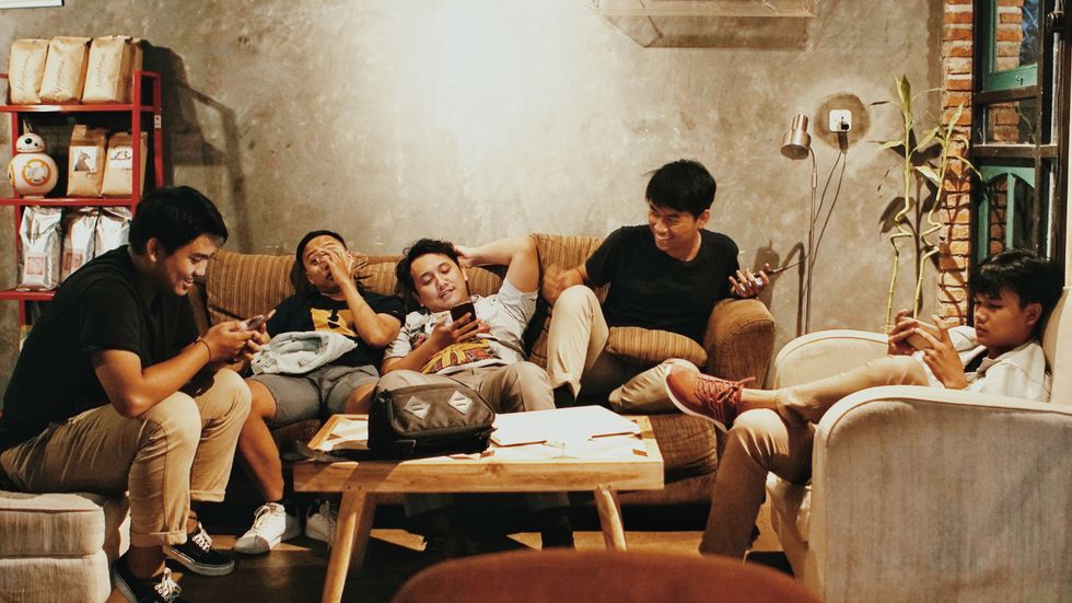 five young men sitting on couches in a house