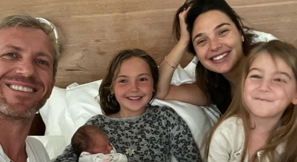 Gal Gadot with husband Jaron Versano and three young children on a bed.