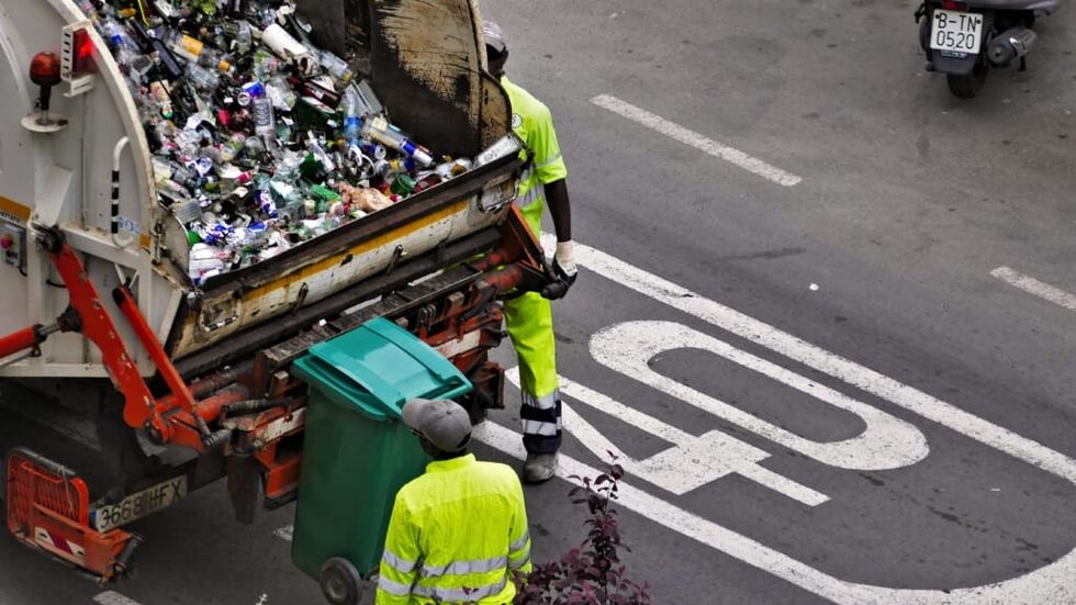 garbage collectors around a truck filled with trash