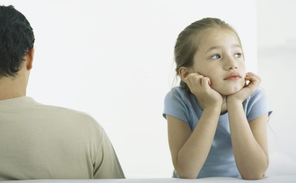 Girl holding head, leaning on elbows next to man, rear view
