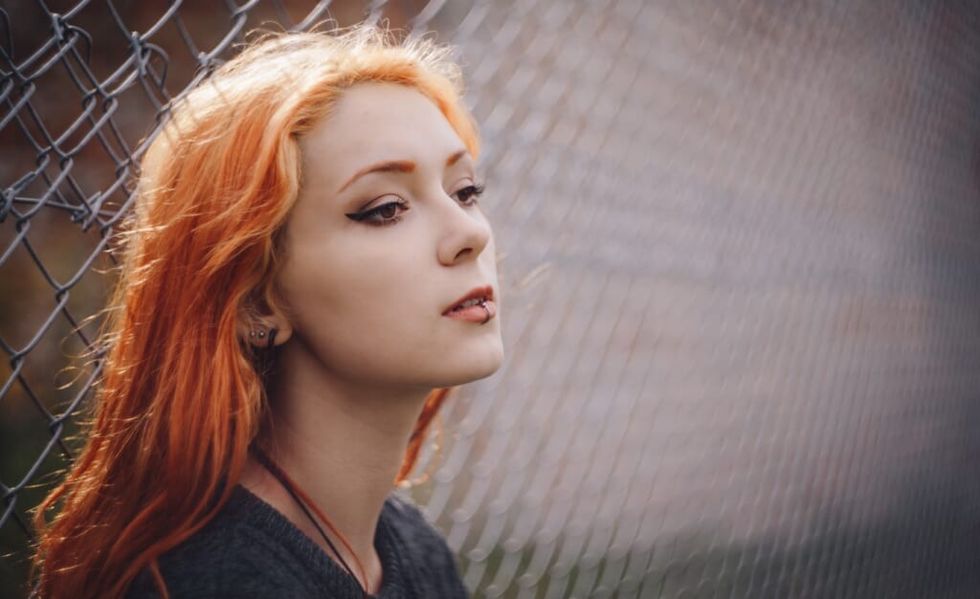 girl poses outside in front of fence