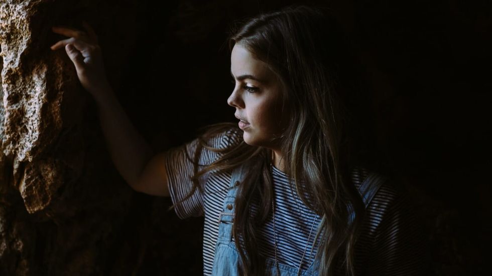 girl standing in a rocky cave