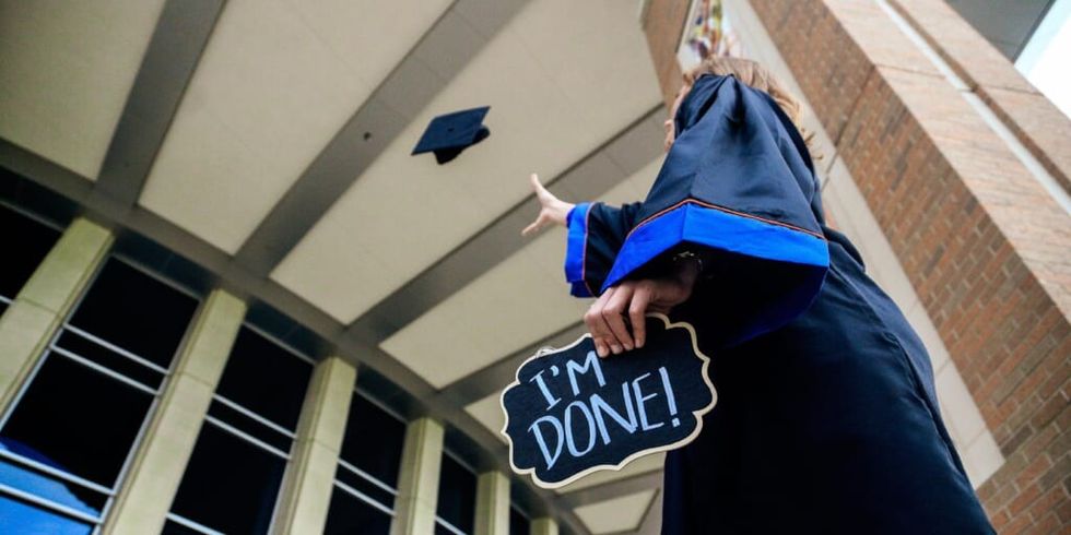Graduate throwing cap in the air holding sign saying I'm done by Chichi Onyekanne on Unsplash