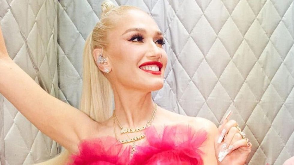 Gwen Stefani in a red dress and wearing red lipstick smiling in a padded room