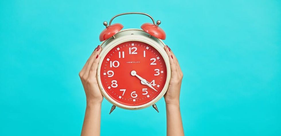 hands holding clock blue background